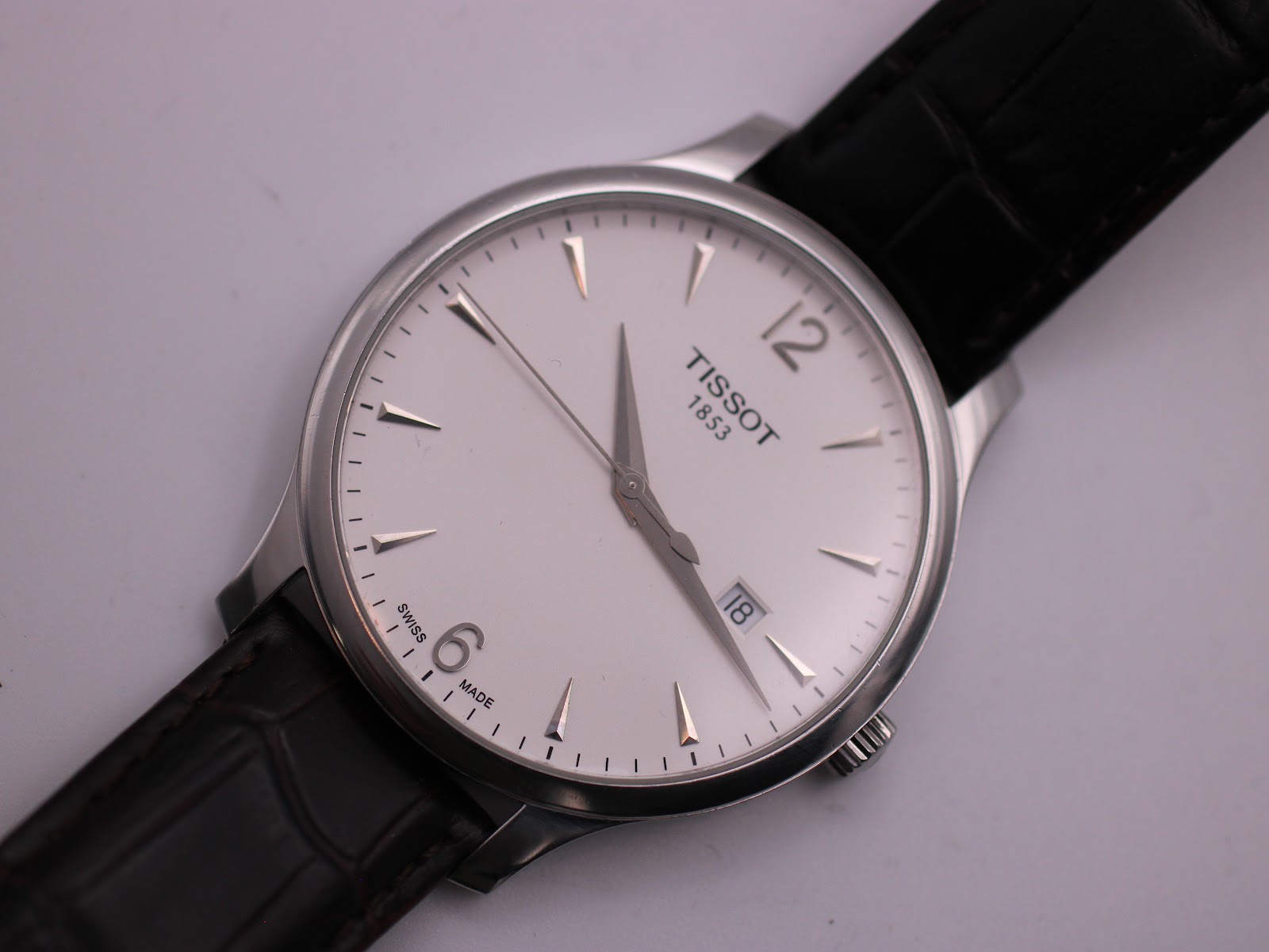 Close-up of the white dial with the Tissot logo, date window, and "Swiss Made" text at the 6 o'clock position.