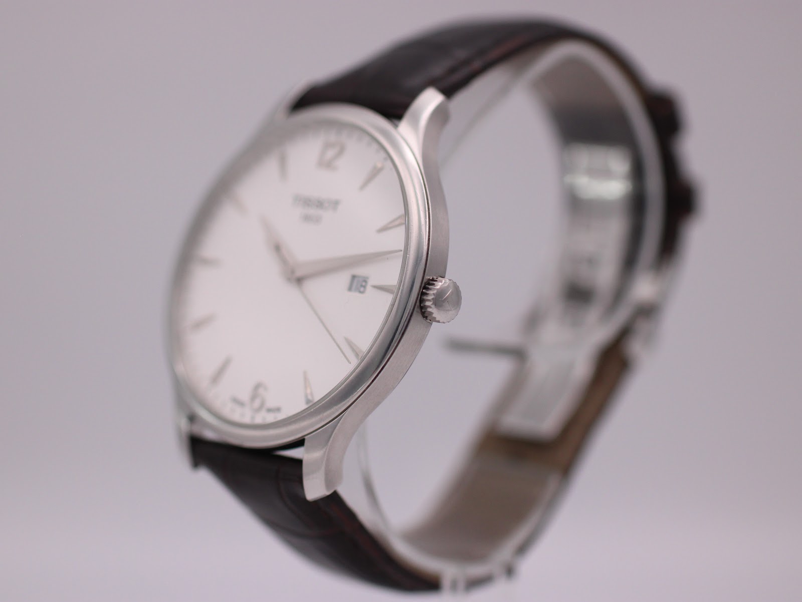 Three-quarter side view of the Tissot T063610 A watch on a display stand, highlighting the polished stainless steel case and crown.