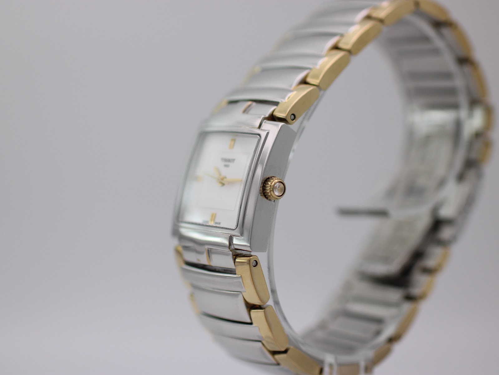 Angled view of the Tissot T051310 A watch, showing the crown and side of the silver case with the gold and silver bracelet.