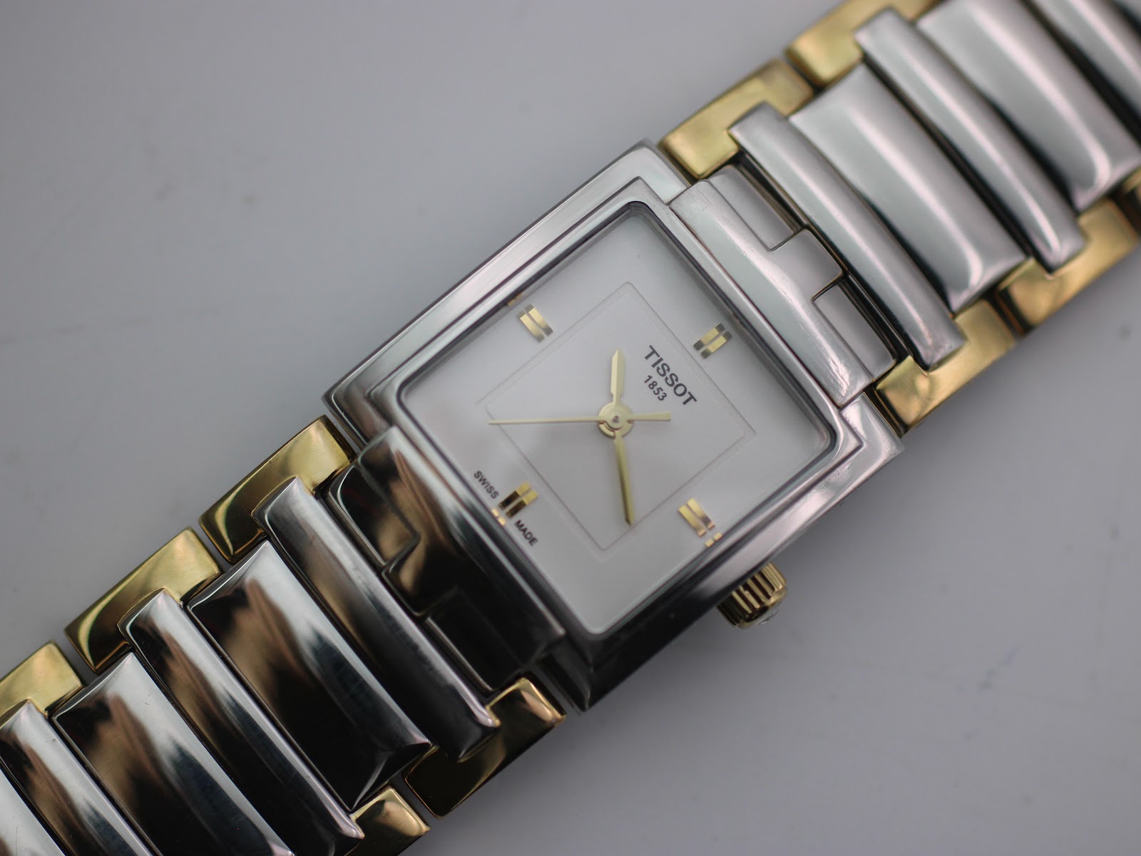 Close-up top-down view of the Tissot watch dial and part of the two-tone bracelet, showing the gold baton markers.