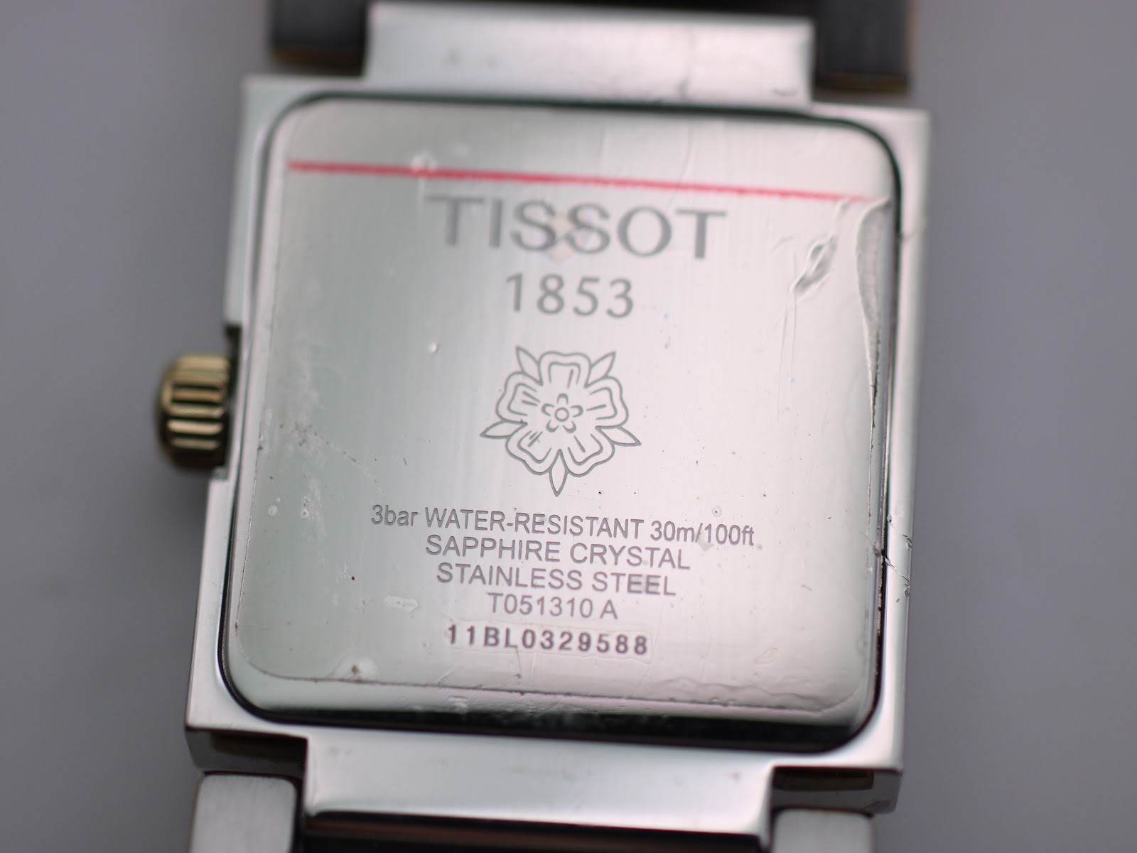 Close-up of the stainless steel case back of the Tissot T051310 A, displaying model number, serial, water resistance, and sapphire crystal details.