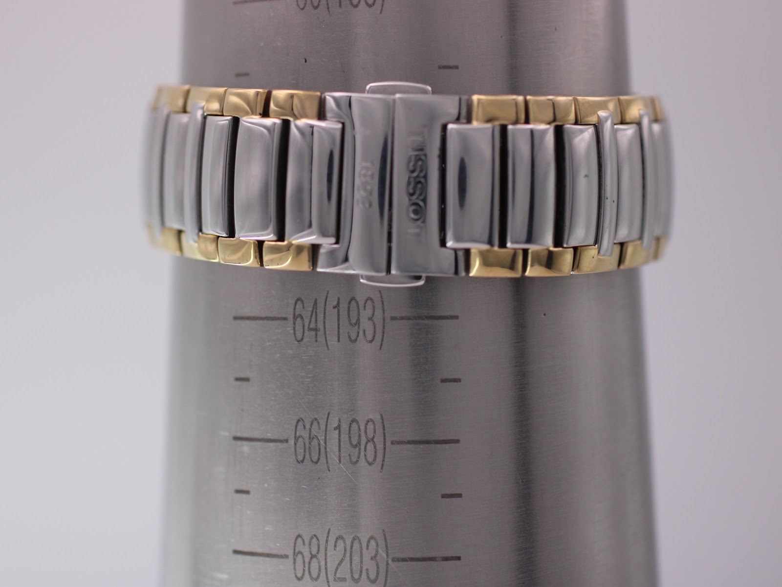 The two-tone Tissot watch bracelet on a wrist sizing gauge, indicating a wrist circumference of 198mm or 19.8cm.