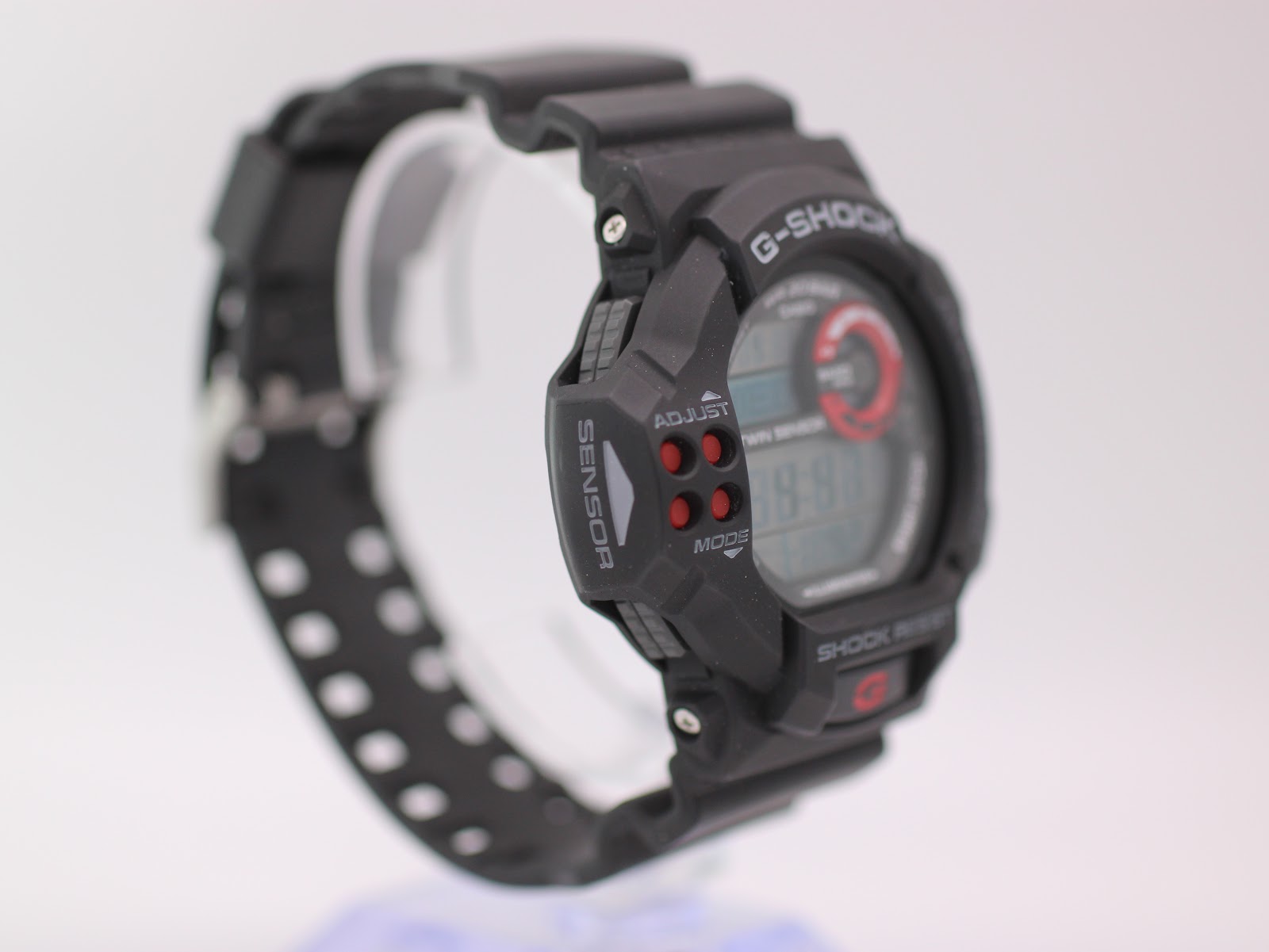 Left-side view of the Casio G-Shock GDF-100 watch on a stand, showing the sensor panel and adjust buttons.