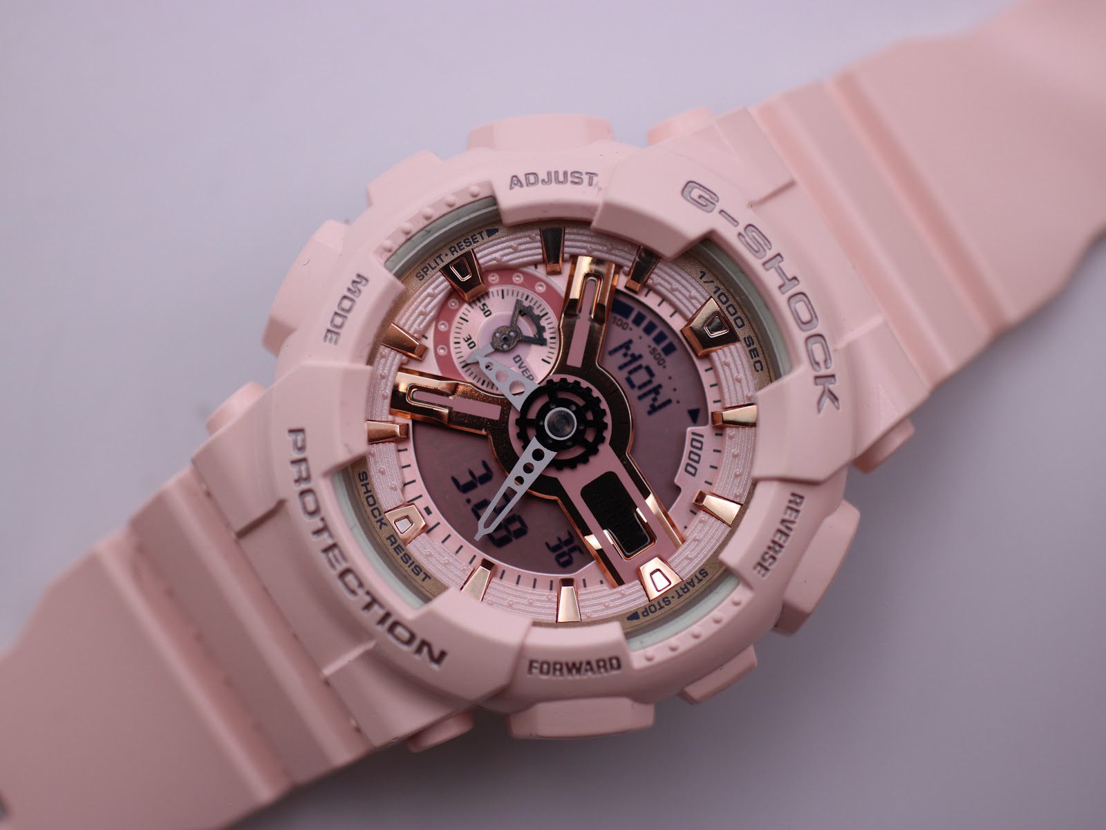 Close-up, angled view of the pink G-SHOCK watch dial, focusing on the ana-digi display and rose gold details.