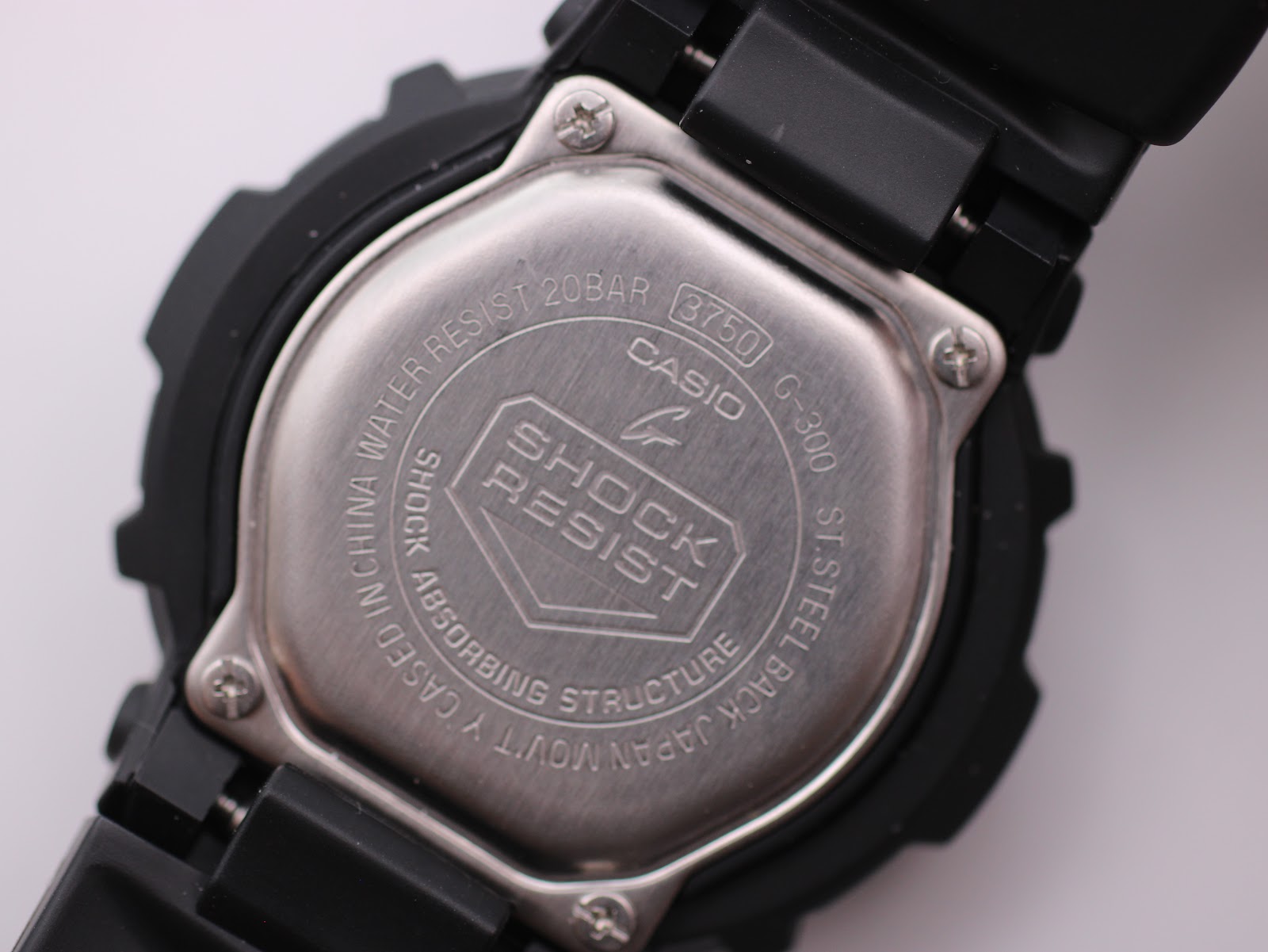 Close-up of the stainless steel case back of the Casio G-Shock G-300, engraved with "SHOCK RESIST", "WATER RESIST 20BAR", "3750", and "G-300".