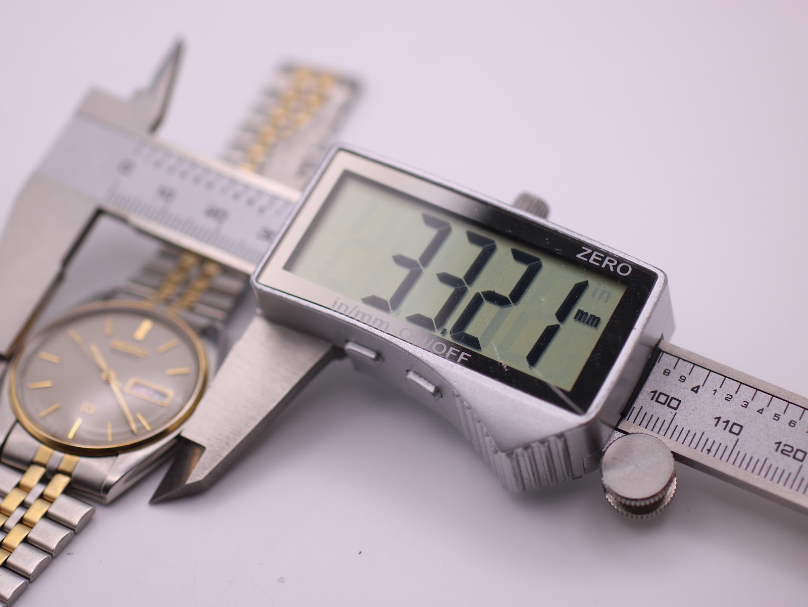 Digital caliper measuring the watch case, displaying '33.21 mm', confirming the precise case diameter.