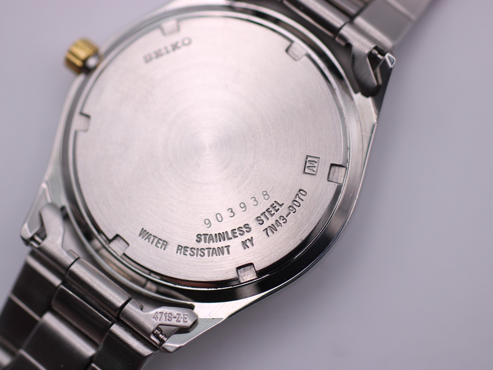 Detailed close-up of the stainless steel case back of the Seiko watch, showing model number 7N43-9070 and "Water Resistant" engraving.
