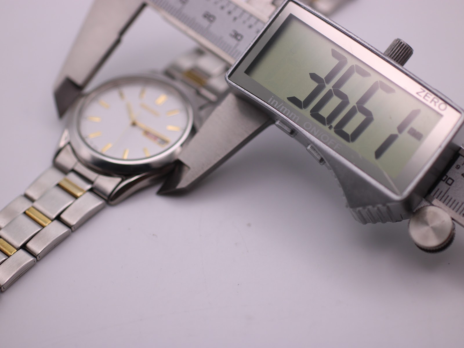 Digital caliper display showing a precise measurement of 36.5mm across the case of the Seiko watch.