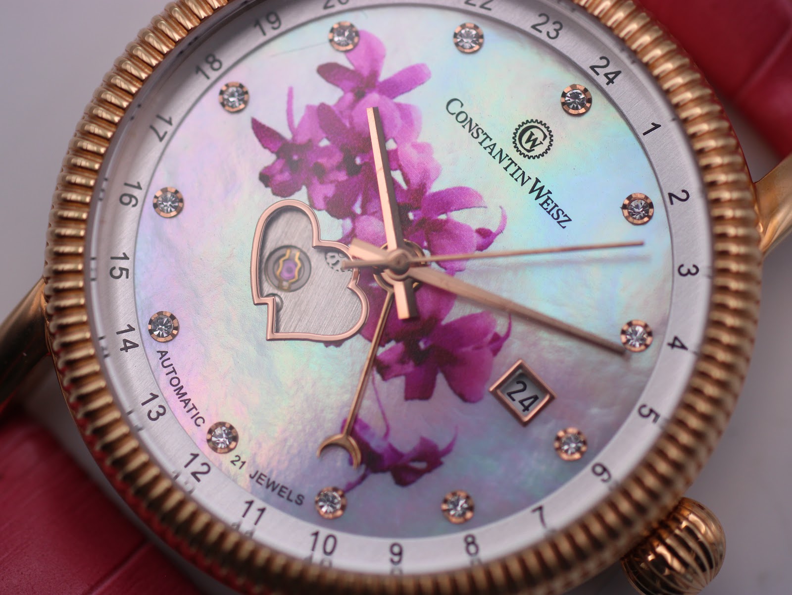 Extreme close-up of the Constantin Weisz dial, bringing out the iridescent lustre of the mother-of-pearl, the individual crystal hour markers, the delicate pink flower motif, and the exposed gears of the open-heart mechanism.