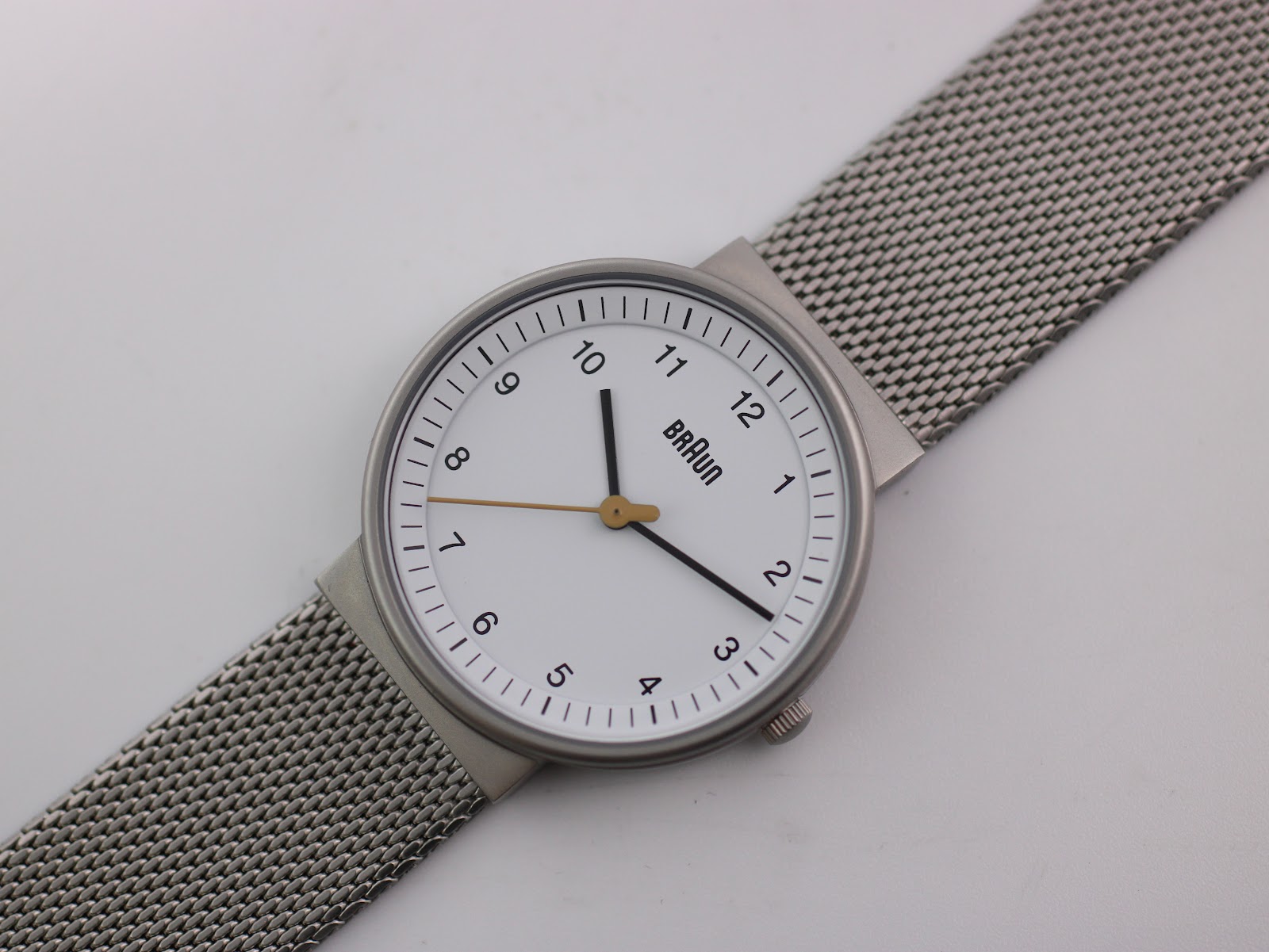 Top-down angled view of the Braun BN0031WHSLMHL watch, displaying the white dial and the silver mesh strap laid flat.