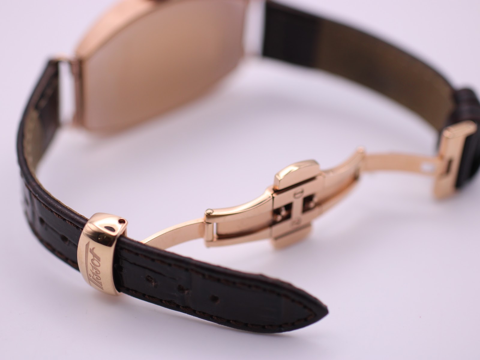 Close-up of the brown leather strap with a rose gold PVD deployant clasp, signed 'Tissot'.