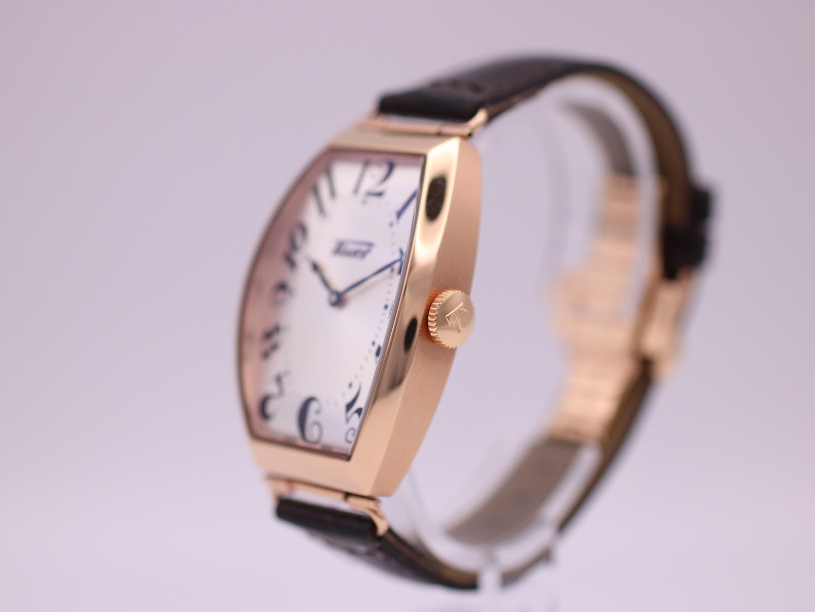 Angled side view of the Tissot T128509 A watch, highlighting the polished rose gold PVD tonneau case and signed crown.