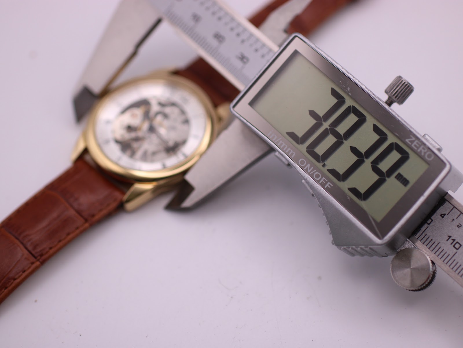 Digital caliper measuring the case diameter of the PWC London watch, displaying a precise measurement of 38.39mm