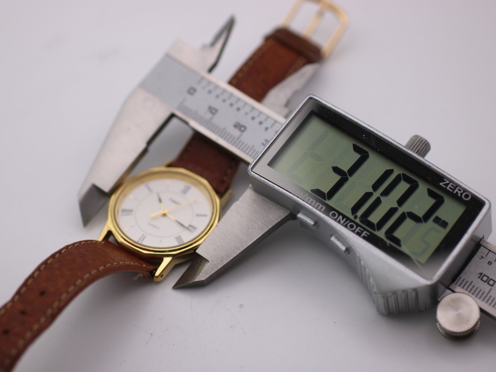 Digital caliper measuring the watch case, displaying 31.02mm.