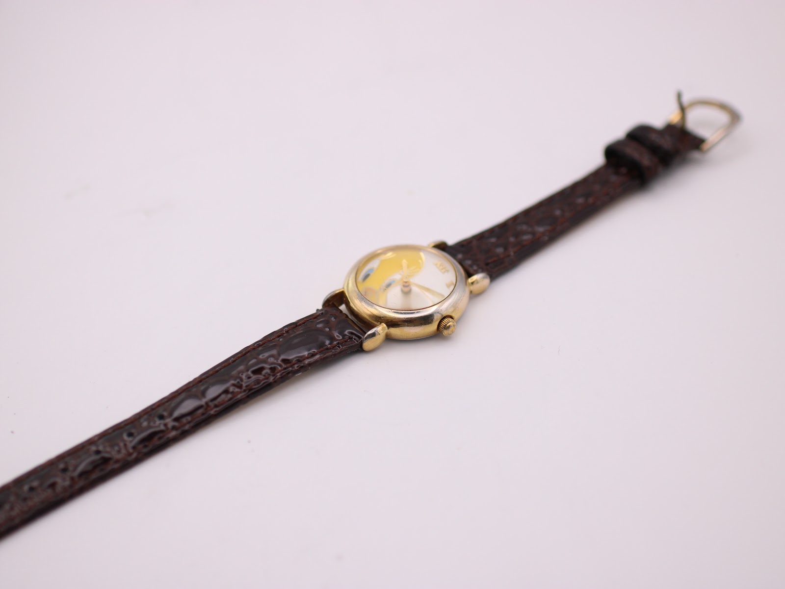 Top-down view of the watch and full length of the brown leather strap with gold-tone buckle on a white background.