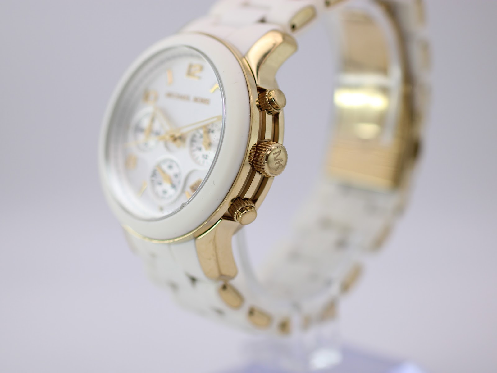 Angled side view of the Michael Kors watch, highlighting the gold-tone crown with MK logo and pushers on the right side of the case.