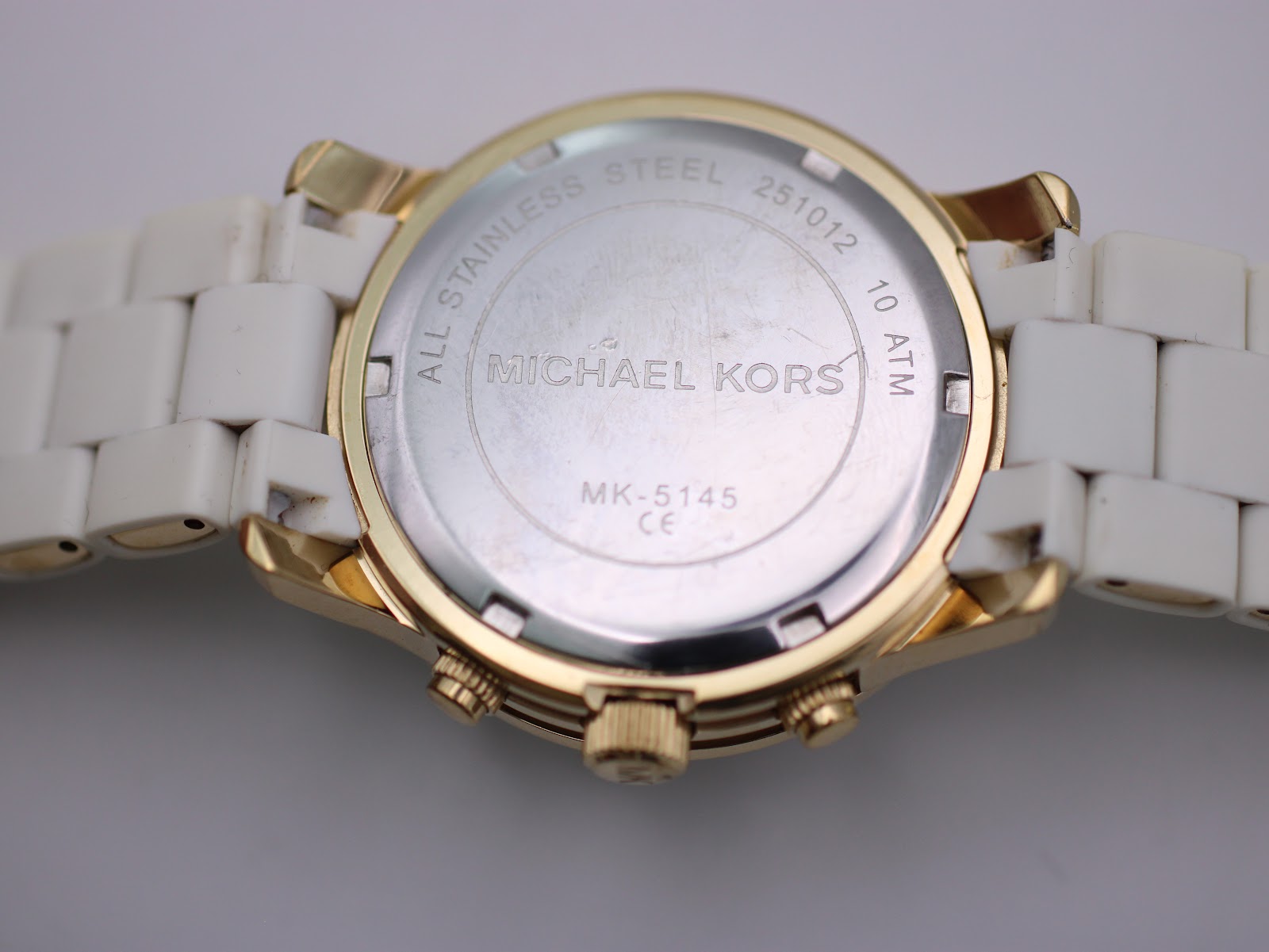 Rear view of the watch case back, showing "MICHAEL KORS", "ALL STAINLESS STEEL", "10 ATM", "MK-5145", and serial number.