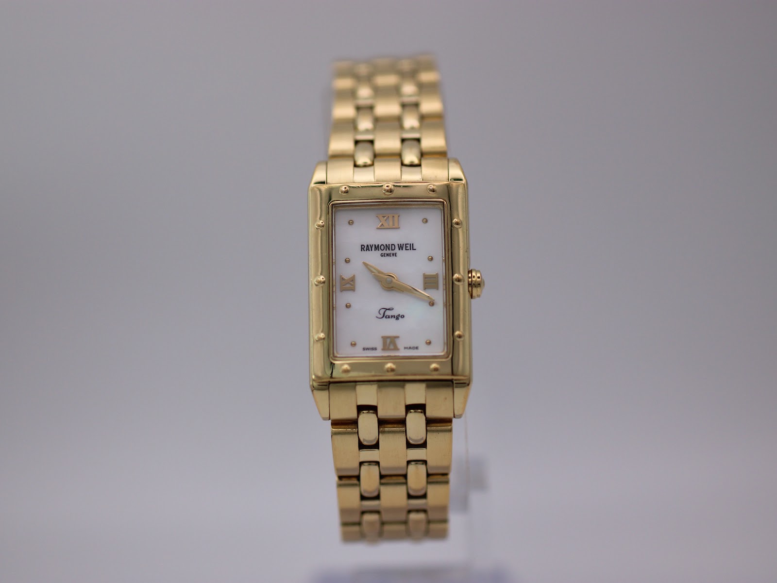 Front view of gold Raymond Weil Tango watch with cream mother-of-pearl dial and rectangular case.