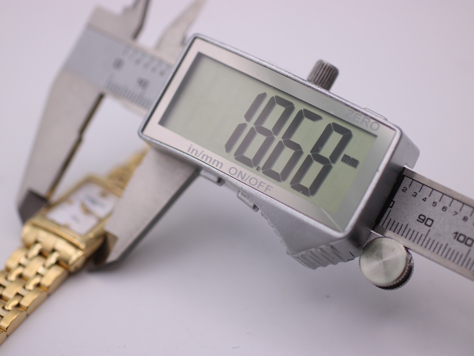 Digital caliper measuring the watch case horizontally, displaying an exact width of 19.68mm on its screen.