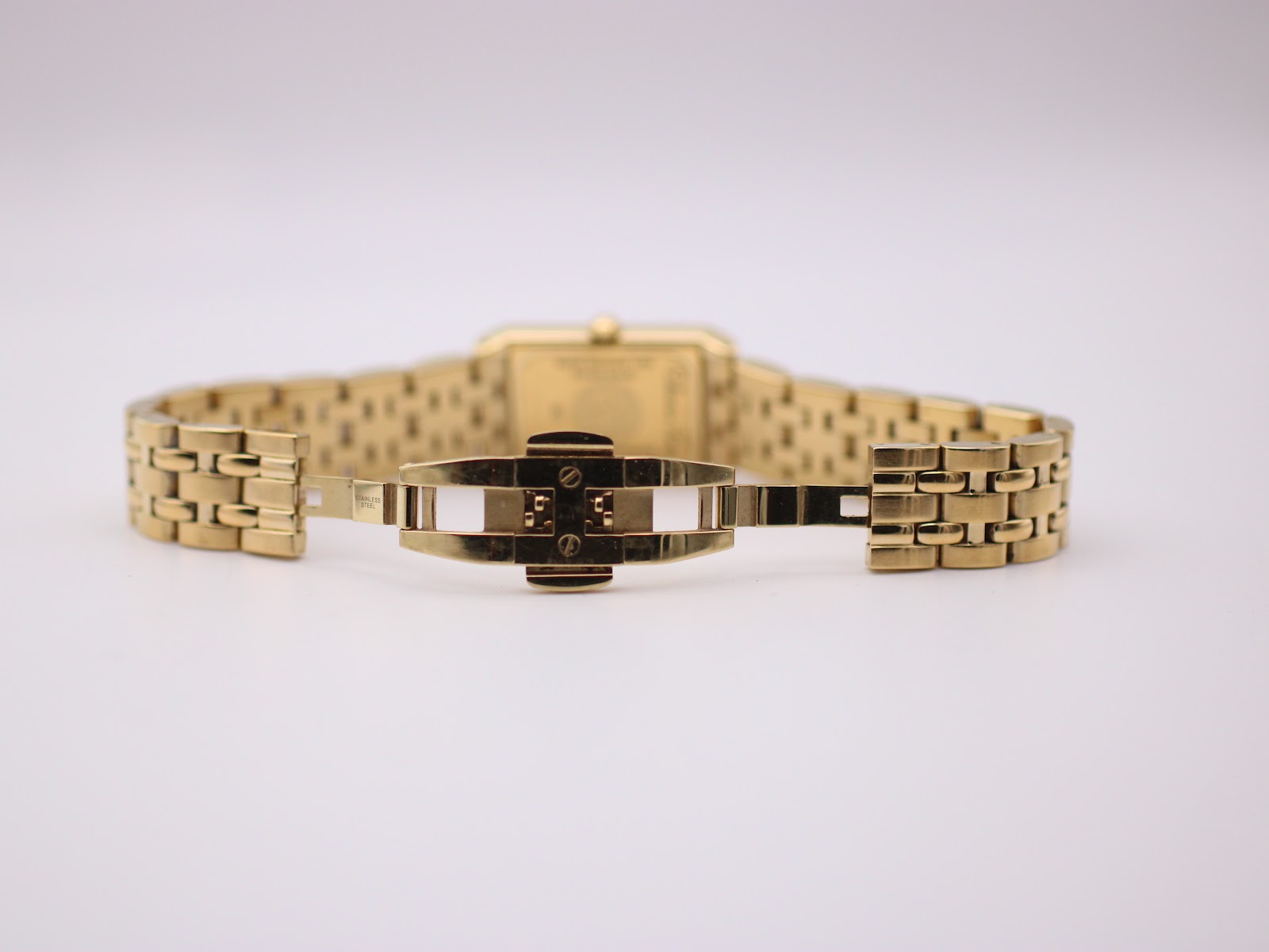 View of the watch's gold-tone steel bracelet with its deployant clasp open, showing the internal mechanism.