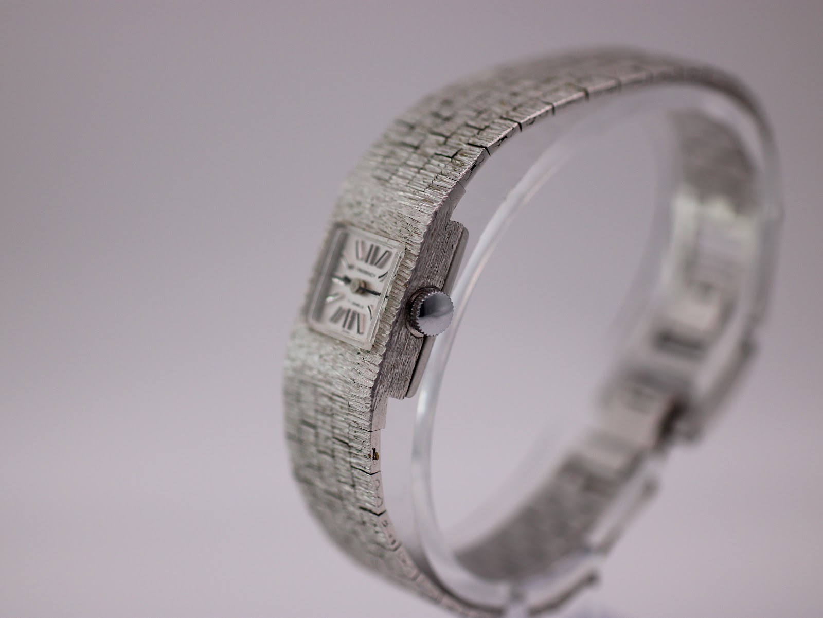 Side view of Regency watch on a display stand, showing the crown and bracelet texture.