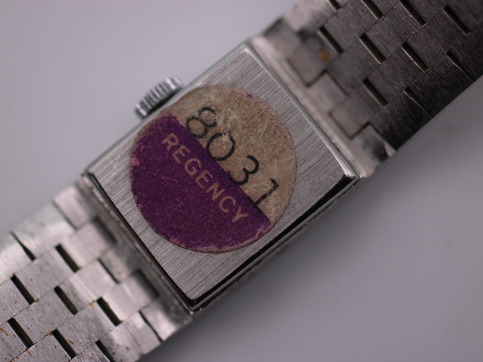 Close-up of the case back with a vintage purple and white 'REGENCY 8031' sticker.