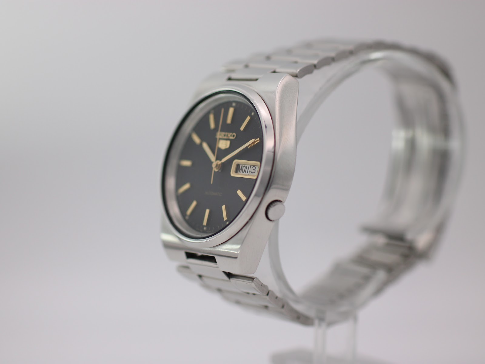 Angled side view of the Seiko watch, showing the cushion case and stainless steel bracelet.