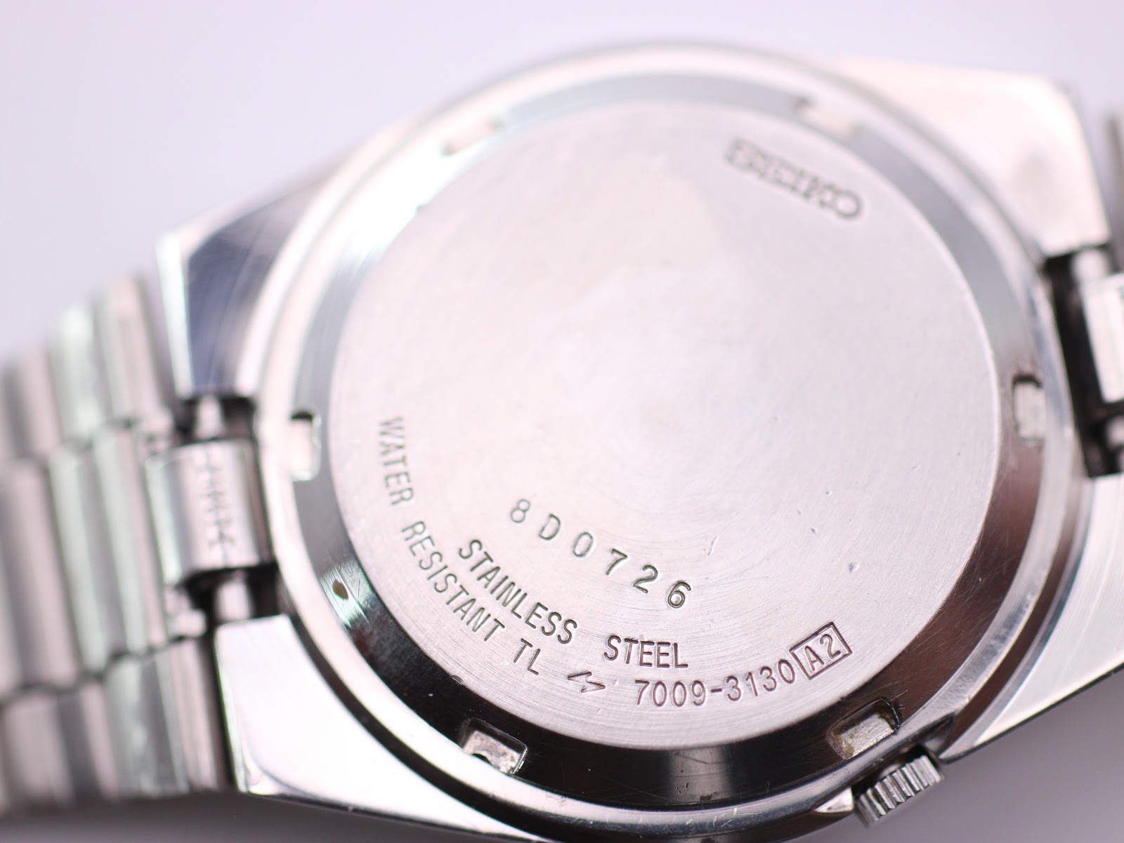 Close-up of the stainless steel case back with "Seiko", "Water Resistant", "Stainless Steel", serial number, and model number engravings.