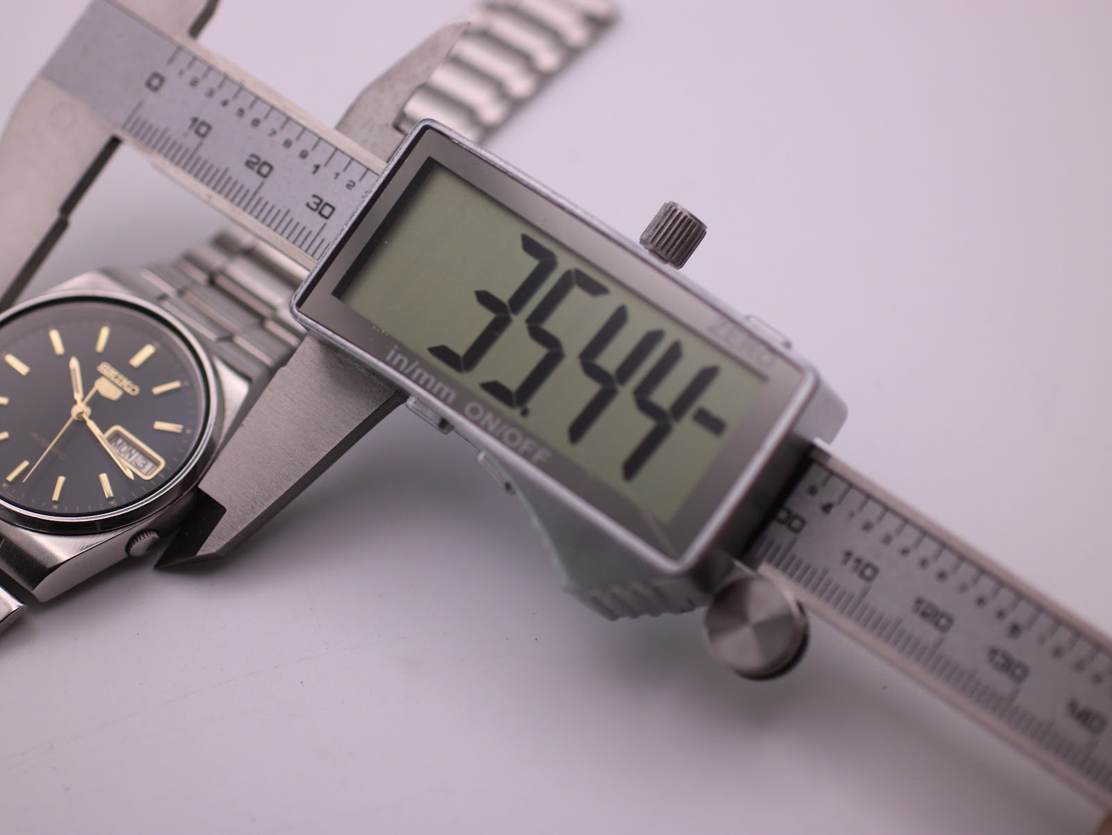 Digital caliper measuring the case diameter of the Seiko watch at 35.44mm.