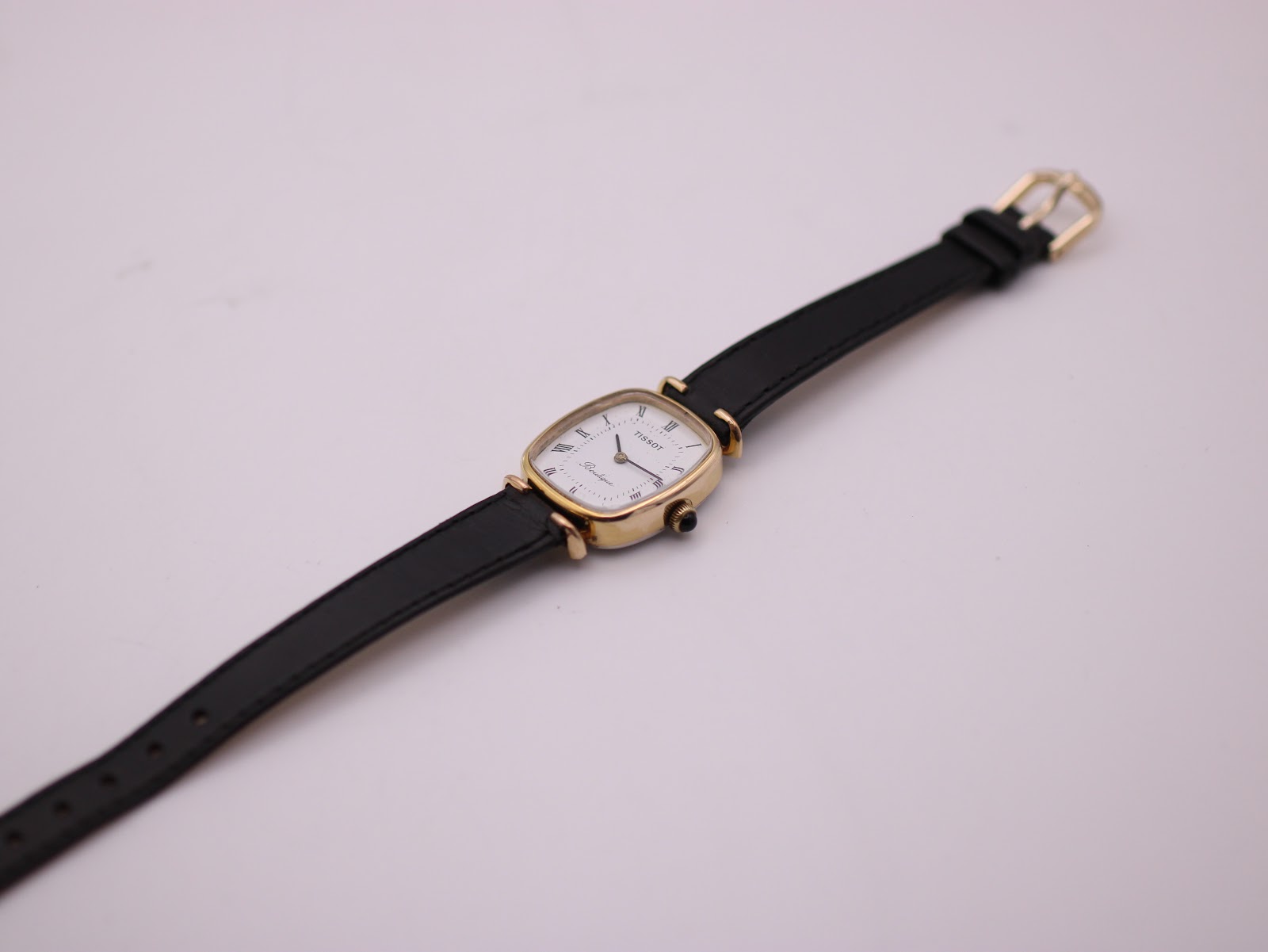 Overhead view of the entire Tissot Boutique watch and strap laid flat on a white surface.