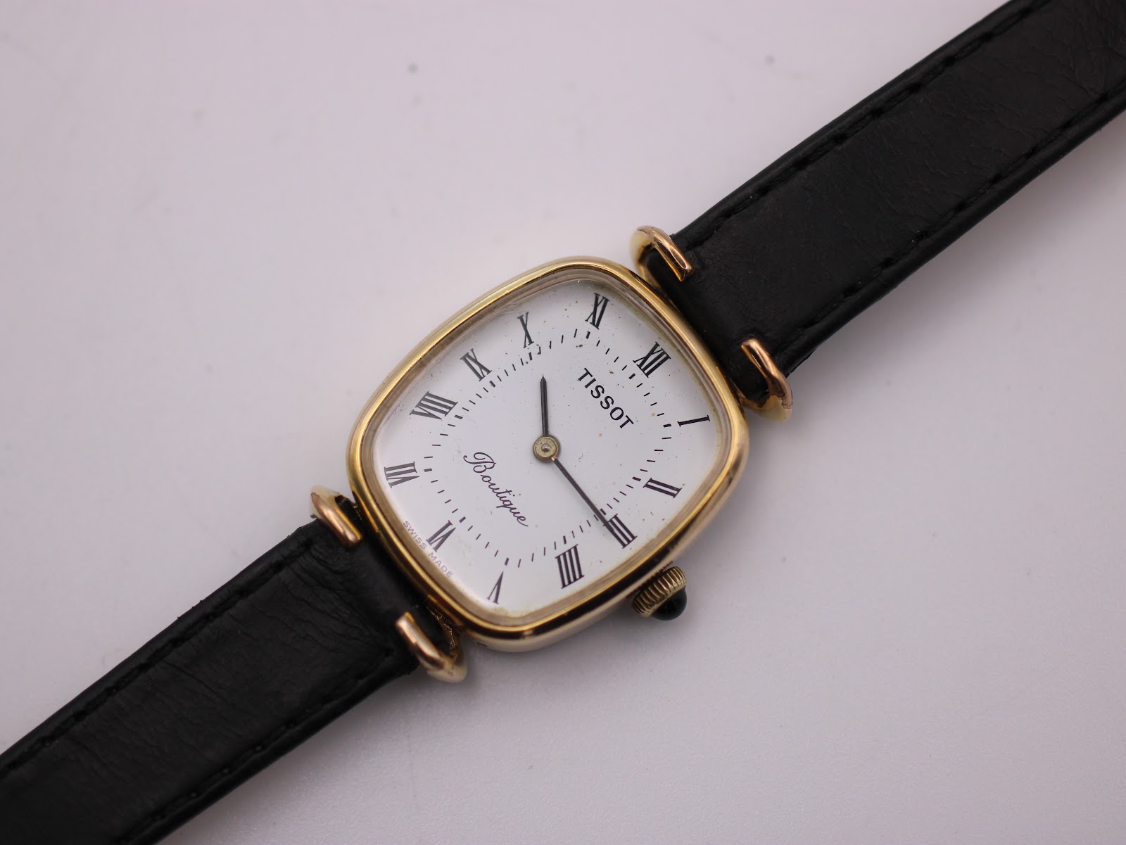 Close-up, slightly angled front view of the Tissot Boutique dial, showing 'TISSOT' and 'Boutique' text.