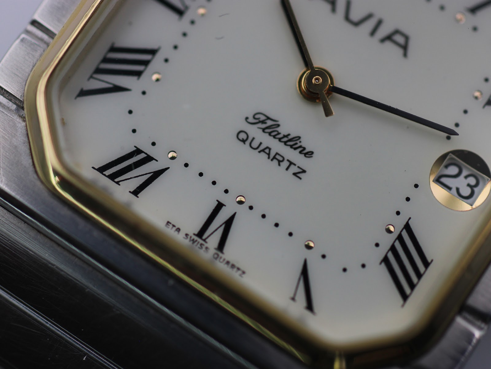 Detailed close-up of the AVIA Flatline dial, focusing on the Roman numeral VI, gold-tone minute track dots, and "ETA SWISS QUARTZ" text.