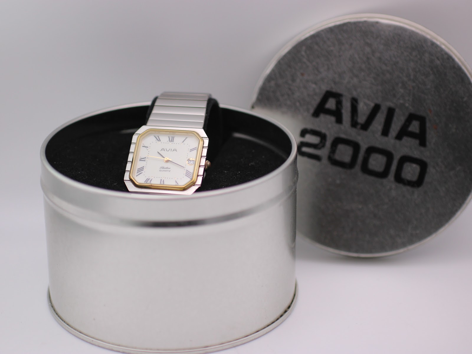 The AVIA Flatline watch presented in its original AVIA 2000 tin box, with the lid next to it.