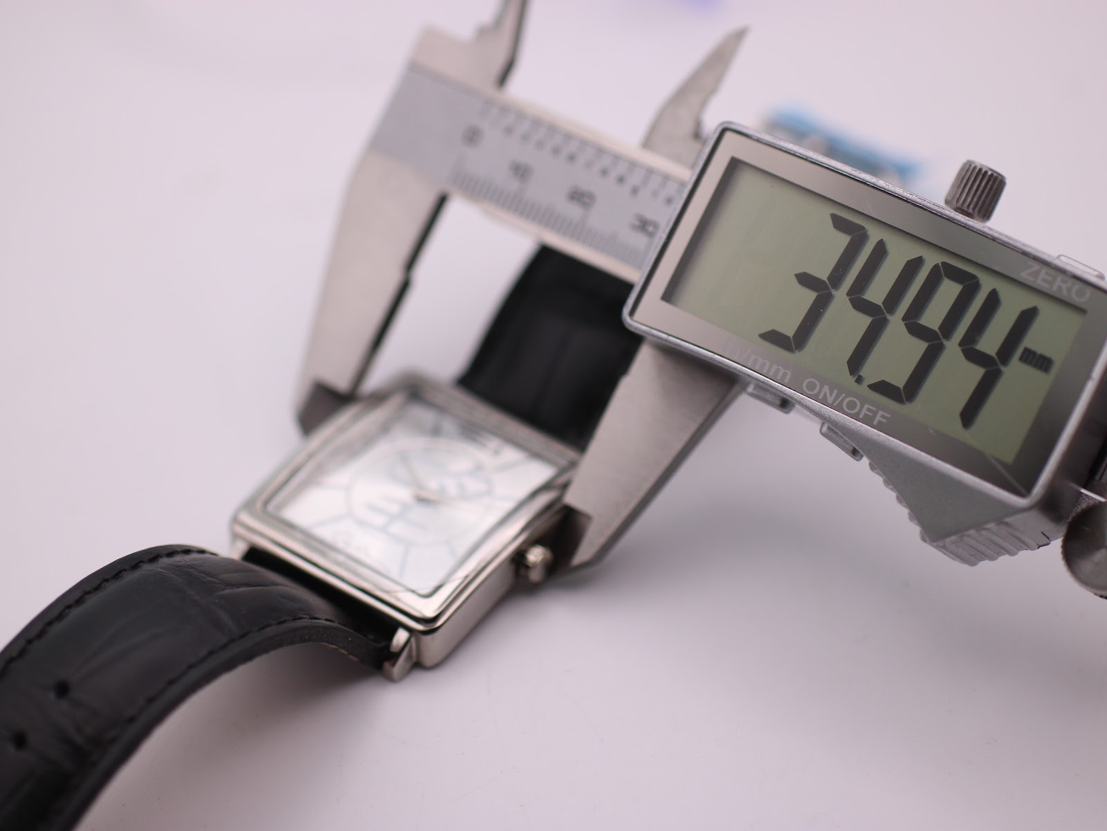 Digital caliper measuring the watch case, showing a precise width of 34.94mm.