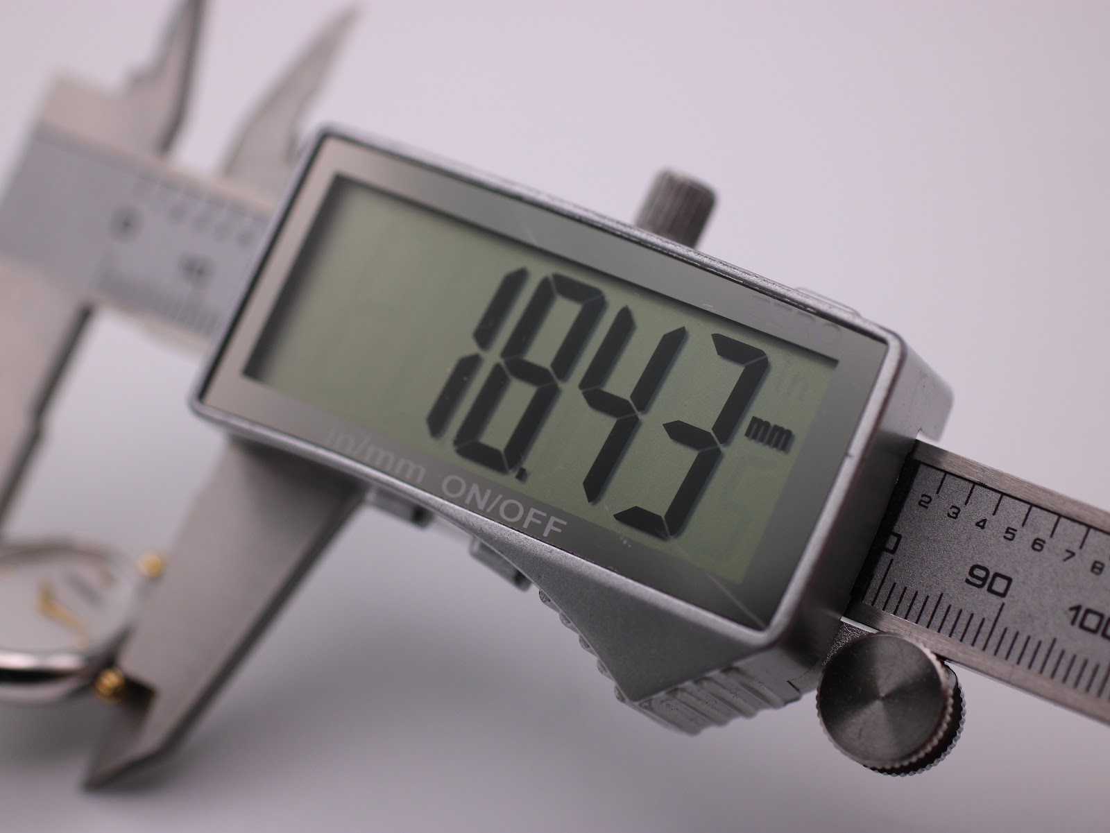 Digital caliper display showing the watch case diameter measurement of 18.43mm.