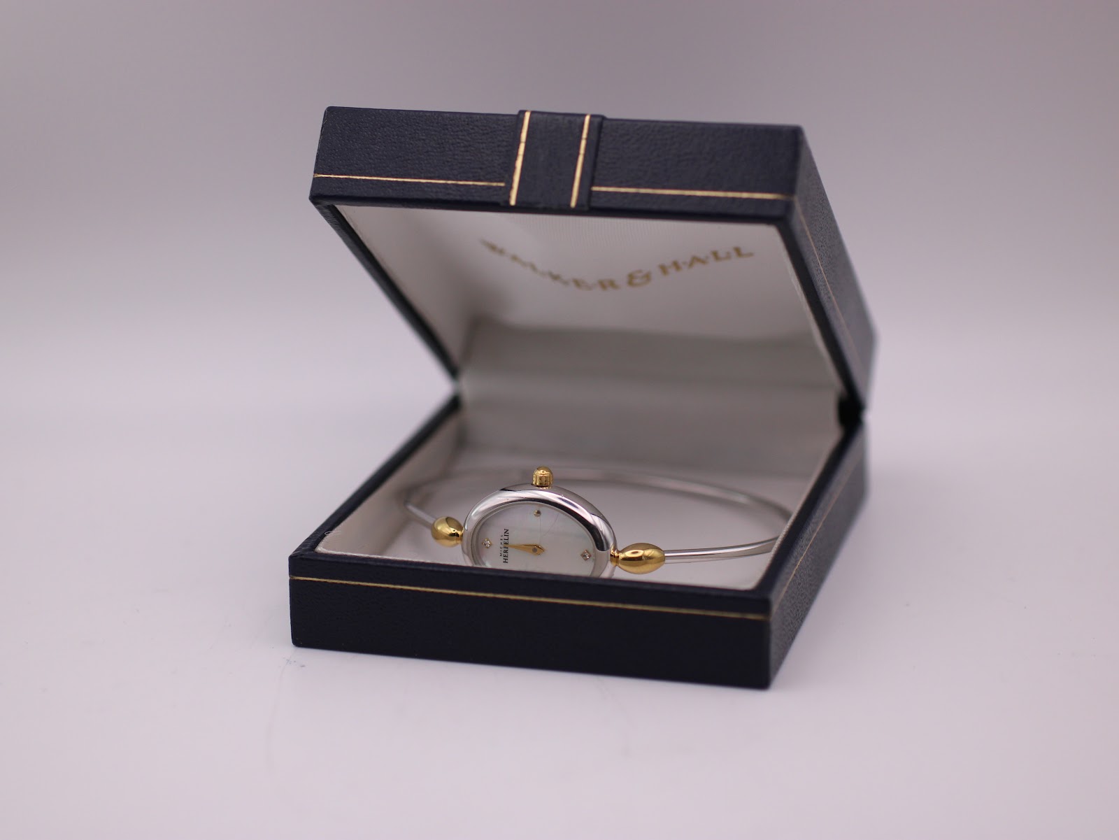 The Michel Herbelin watch displayed open in a dark blue presentation box with gold detailing.