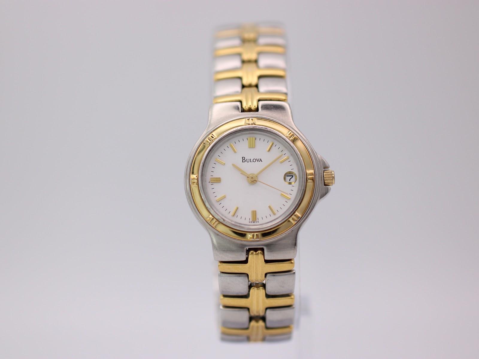 Front view of the Bulova two-tone quartz watch with a white dial and gold-tone baton indices.