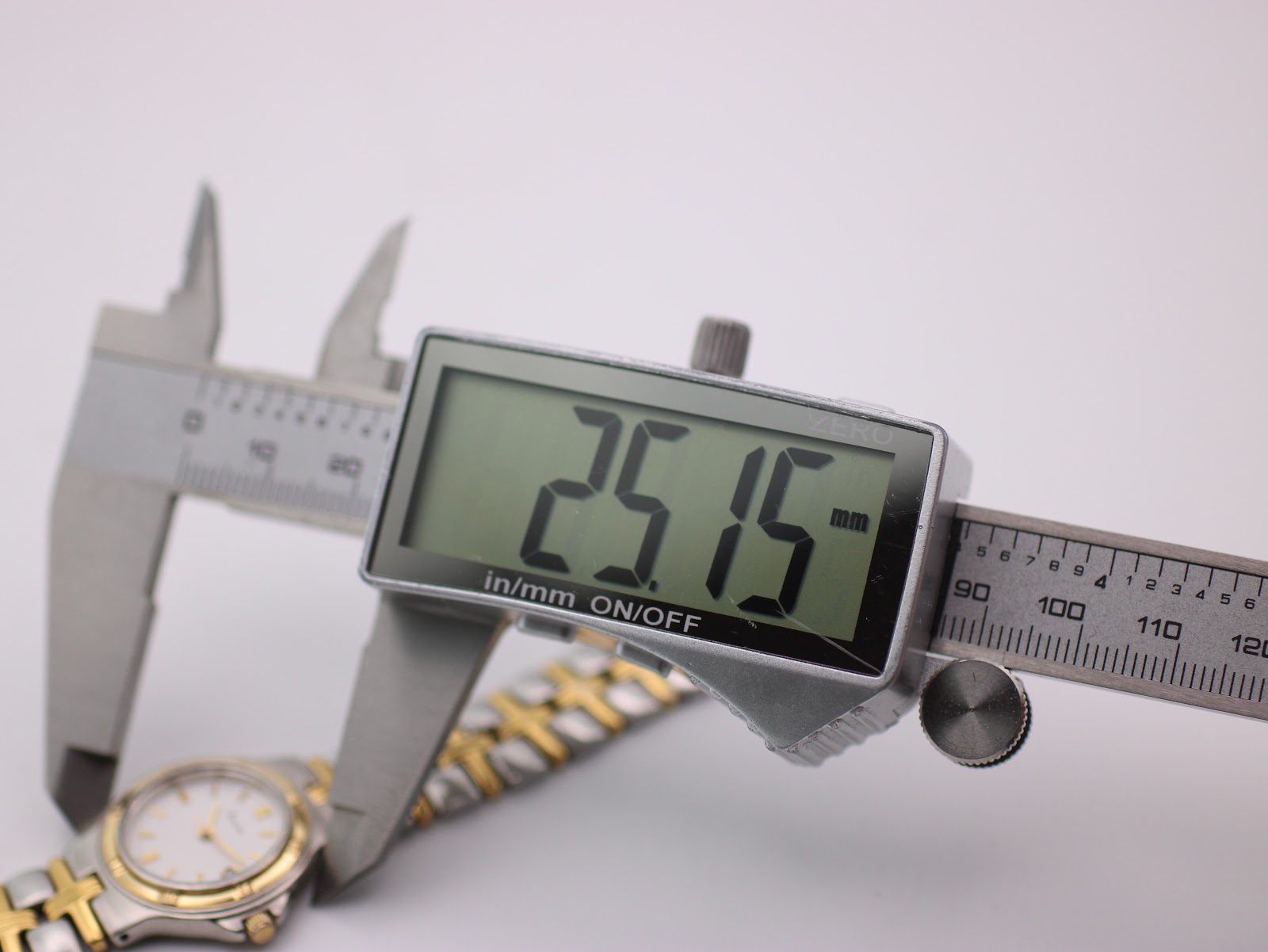 Digital caliper precisely measuring the watch case diameter, displaying 25.15 mm.