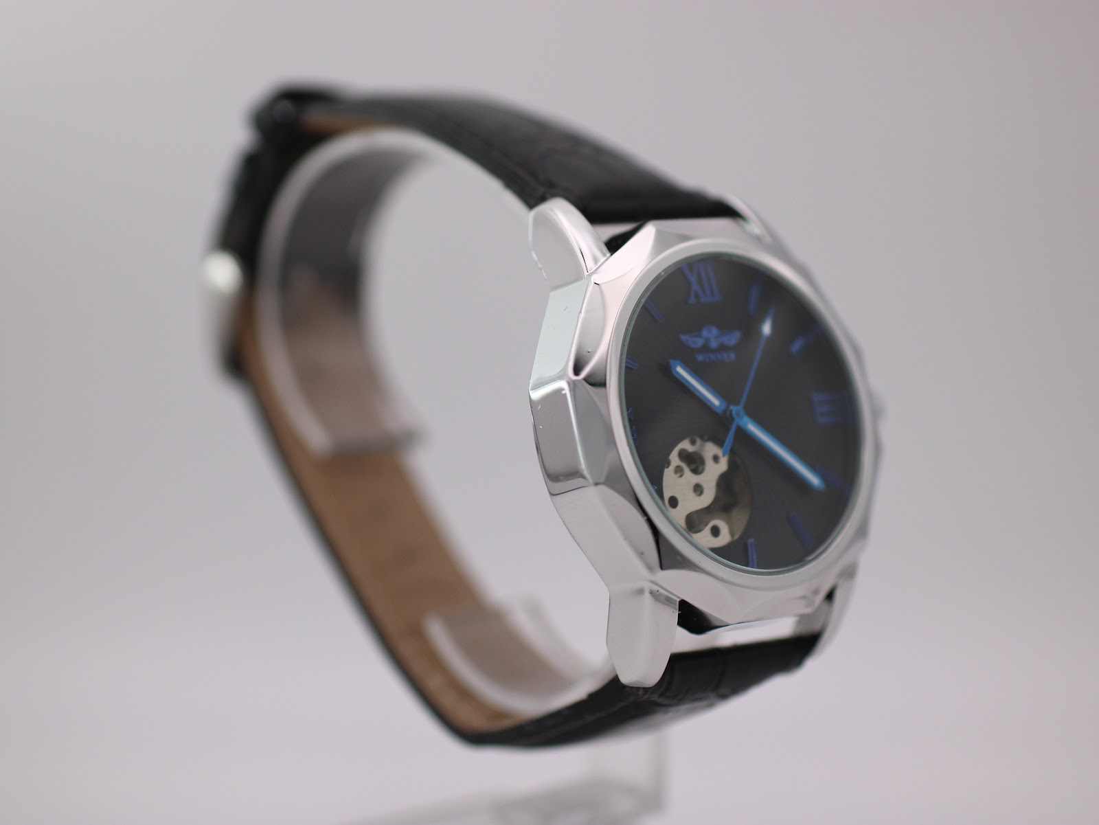Angled side view of Winner H199M watch, highlighting the case facets and black leather strap.