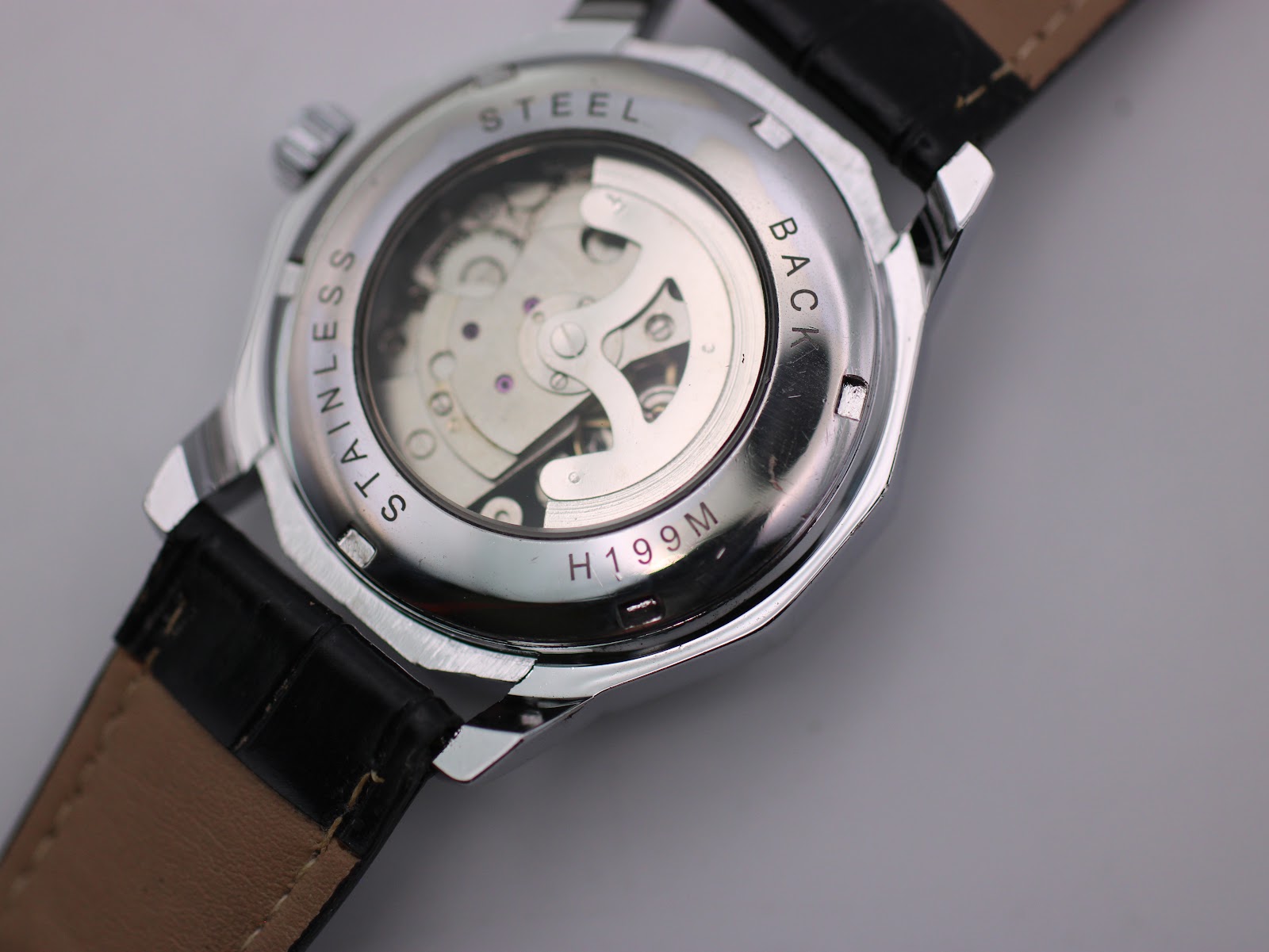 Close-up of the Winner H199M watch case back, showing a display window for the automatic movement and "STAINLESS STEEL BACK H199M" engraving.