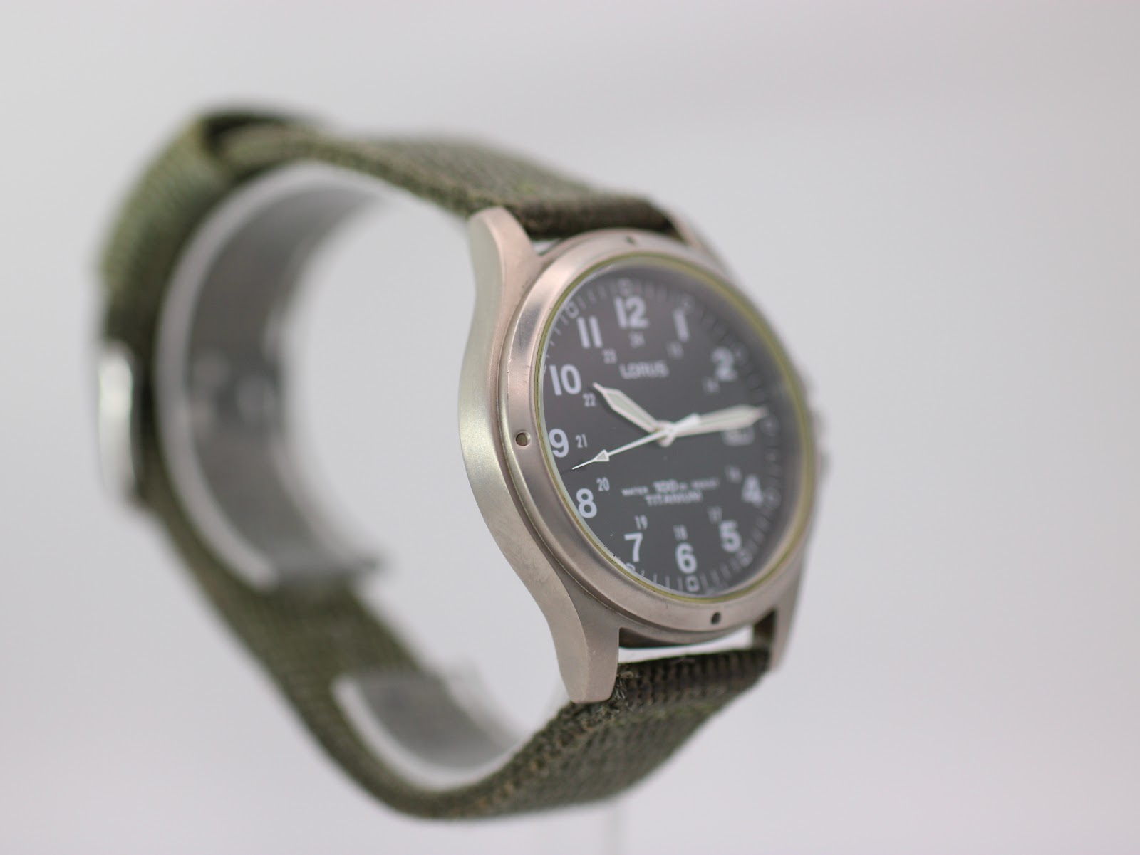 Angled side view of Lorus titanium watch on display stand, showing the case profile.