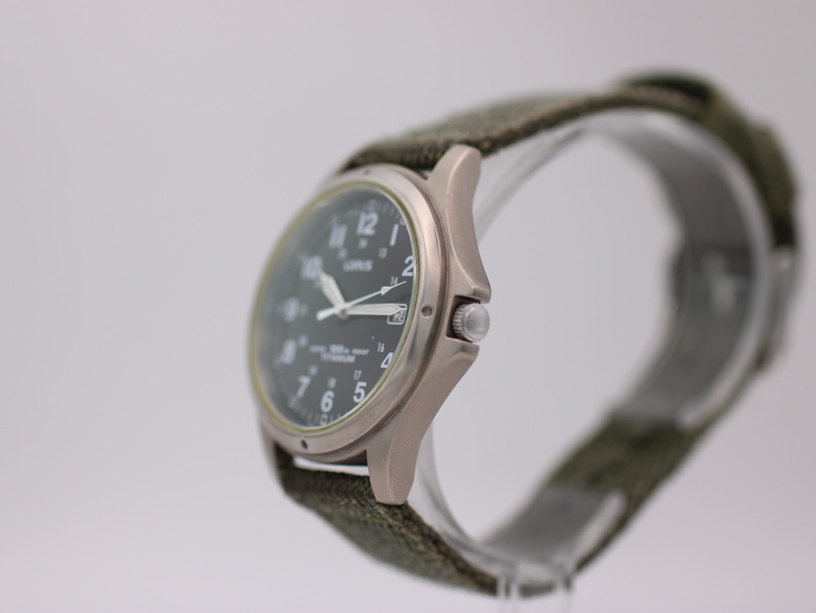 Side view of Lorus titanium watch, crown visible, on display stand.