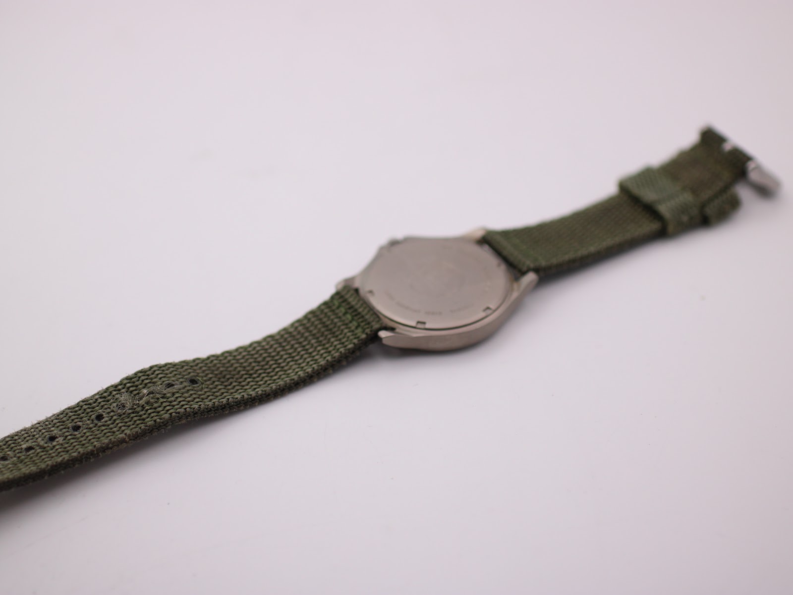 Reverse full length view of Lorus watch with green fabric strap, showing case back details.