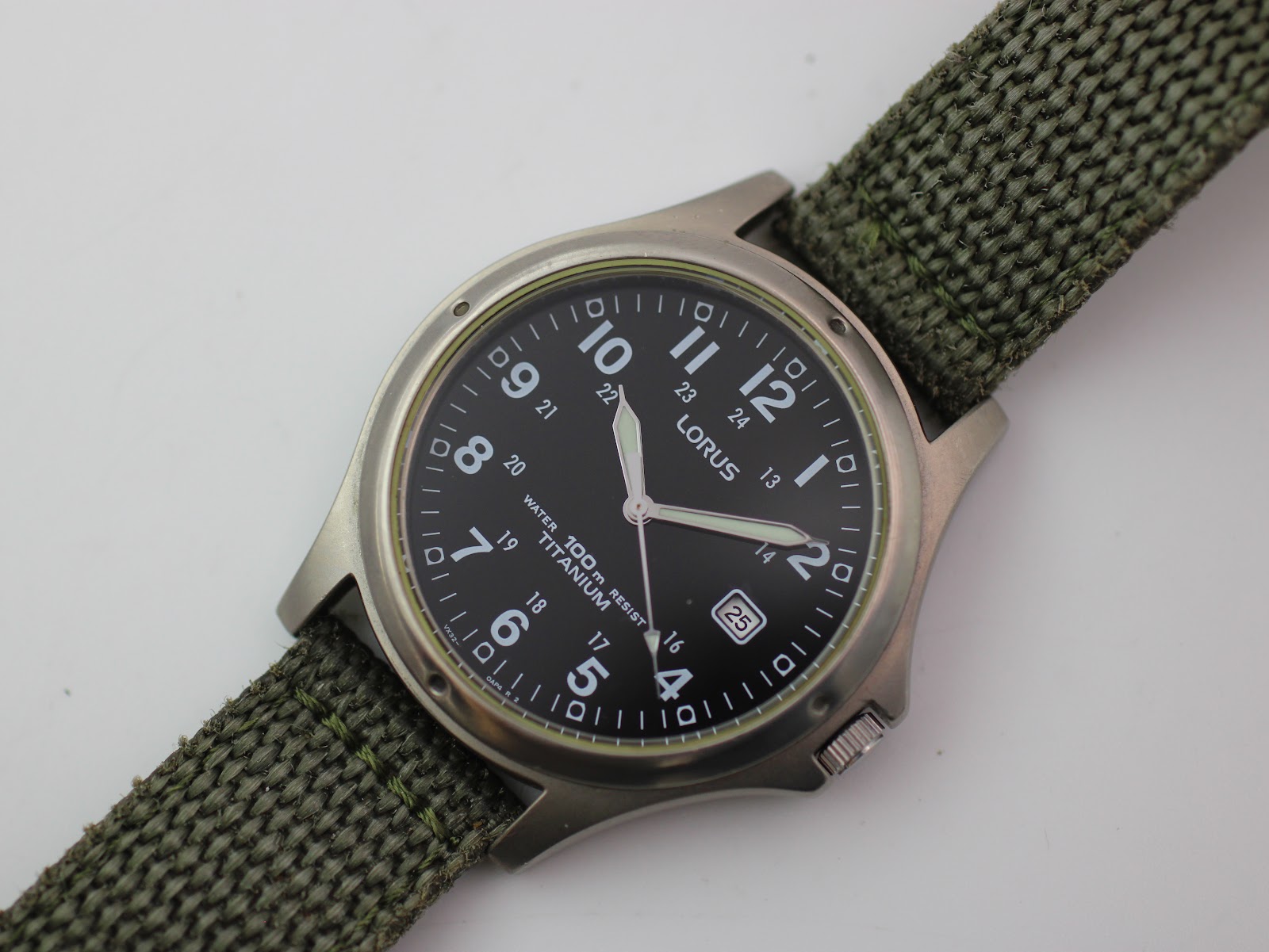 Close-up front view of Lorus black dial, showing Arabic numerals, 24-hour track, date, and luminous hands.