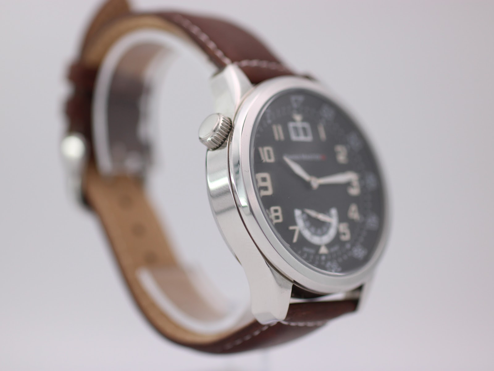 Another angled side view of the Swiss Master watch, showing the case profile and the brown leather strap curving away.