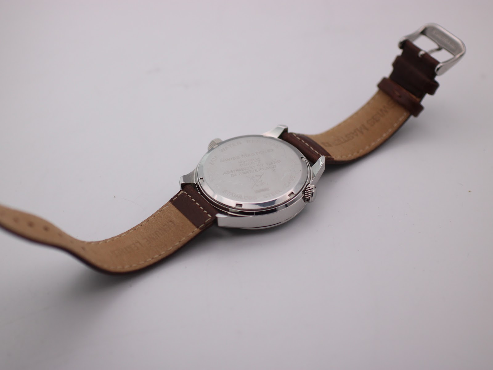 View of the watch case back, showing the 'STAINLESS STEEL CASE' and brown leather strap from behind.
