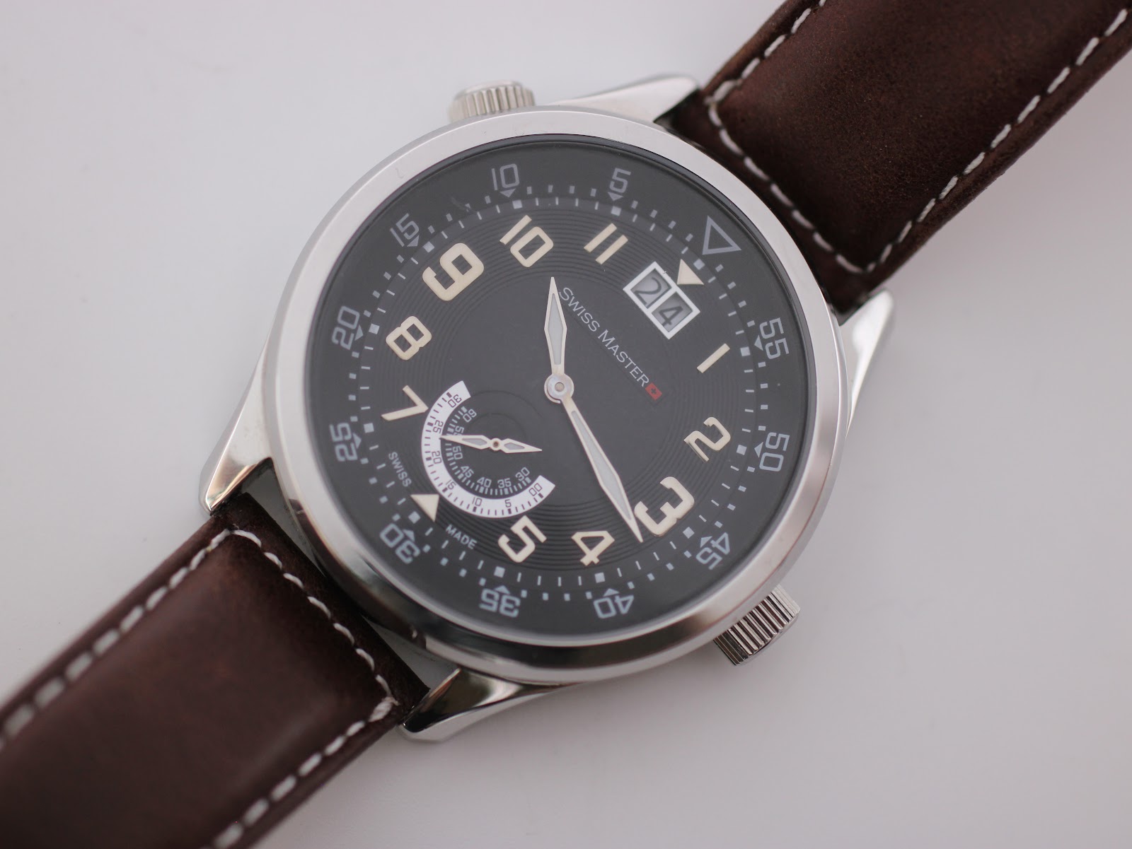 Close-up, slightly angled view of the Swiss Master black dial, showing the large numerals, date window at 12, and sub-seconds dial at 6.