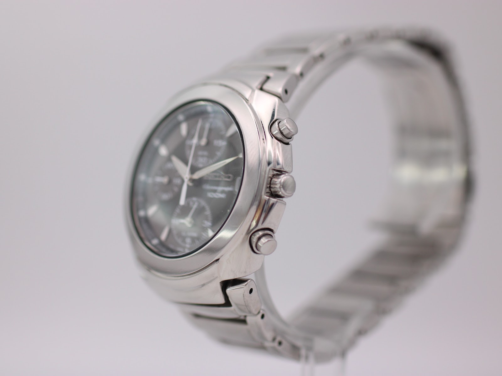 Side-angle view of the Seiko chronograph watch showing the case profile, pushers, and crown, with the bracelet in soft focus.
