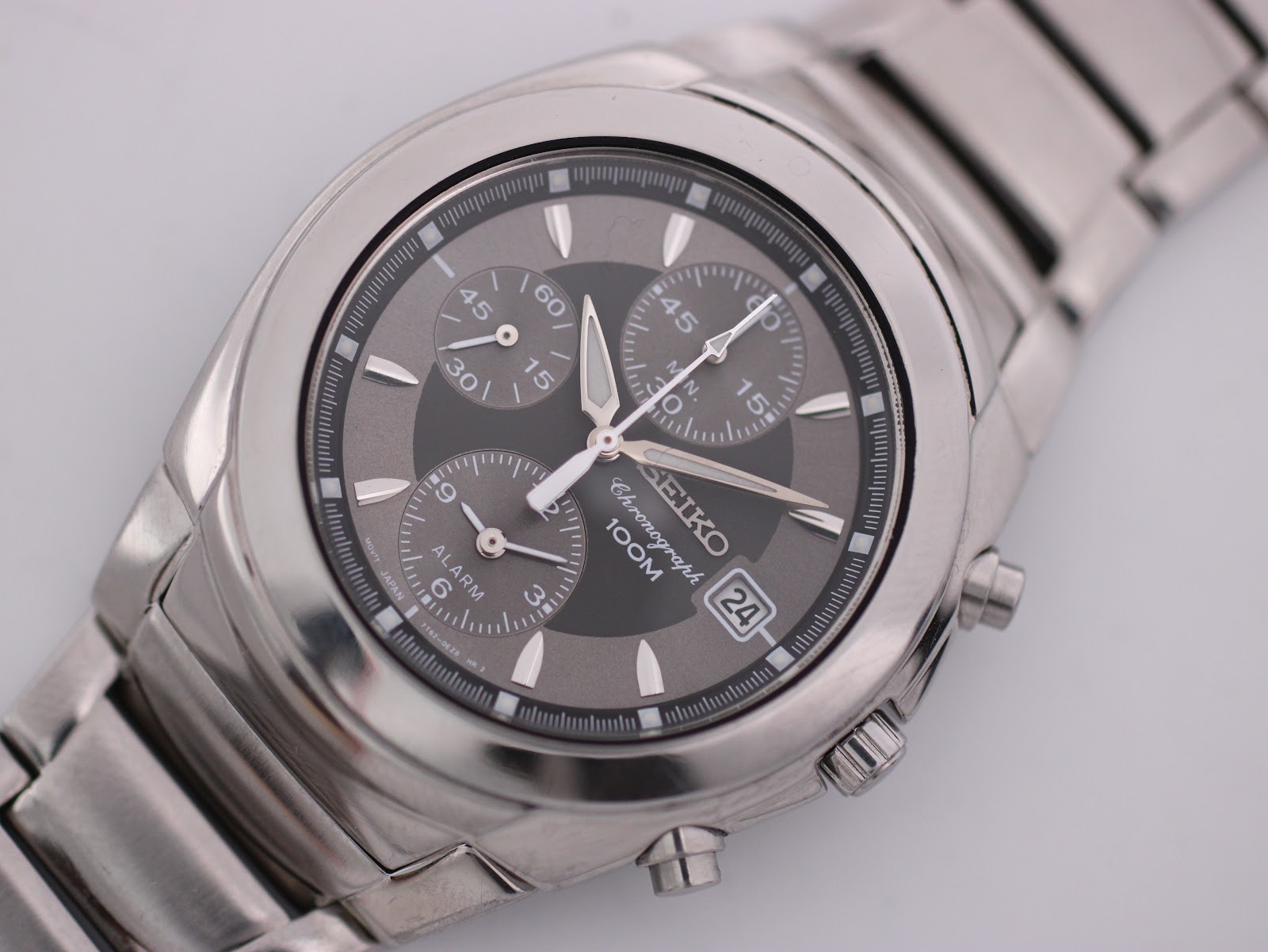 Close-up front view of the Seiko grey multi-register dial, showing the date window, luminous baton indices, and chronograph sub-dials.