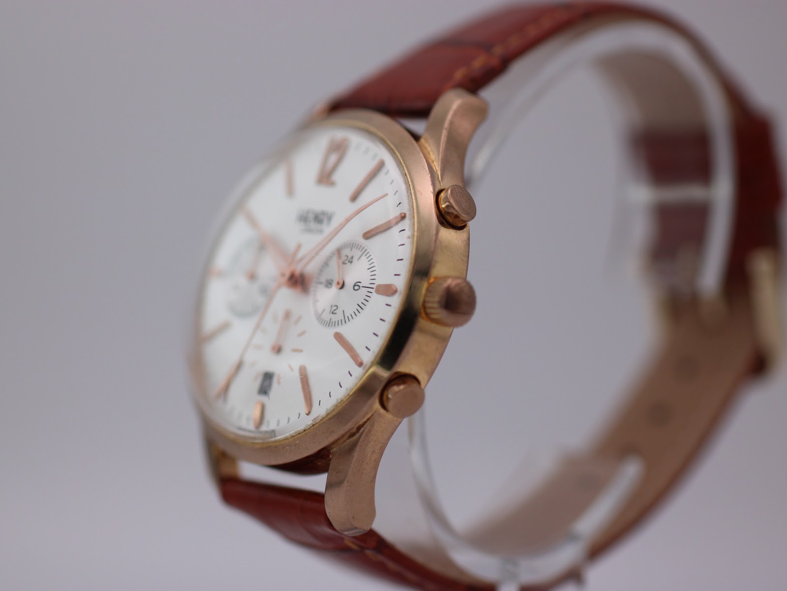 Side profile of the Henry London Pimlico watch on a stand, showing the rose gold crown and pushers.